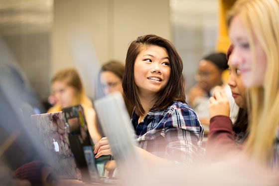 Photo of a young Chatham University student in a lecture hall, surrounded by classmates