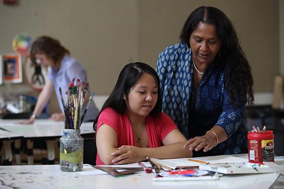 Photo of a Chatham University professor wearing a sari assisting a student in art lab.