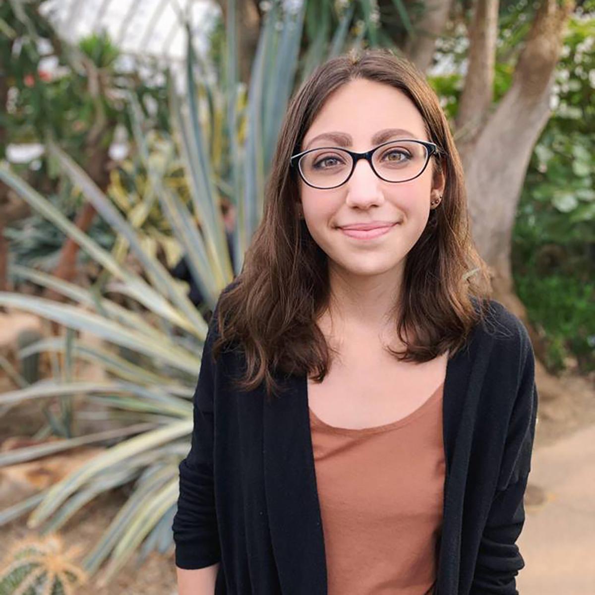 Portrait of Elana Ragan, a woman with glasses, standing outside